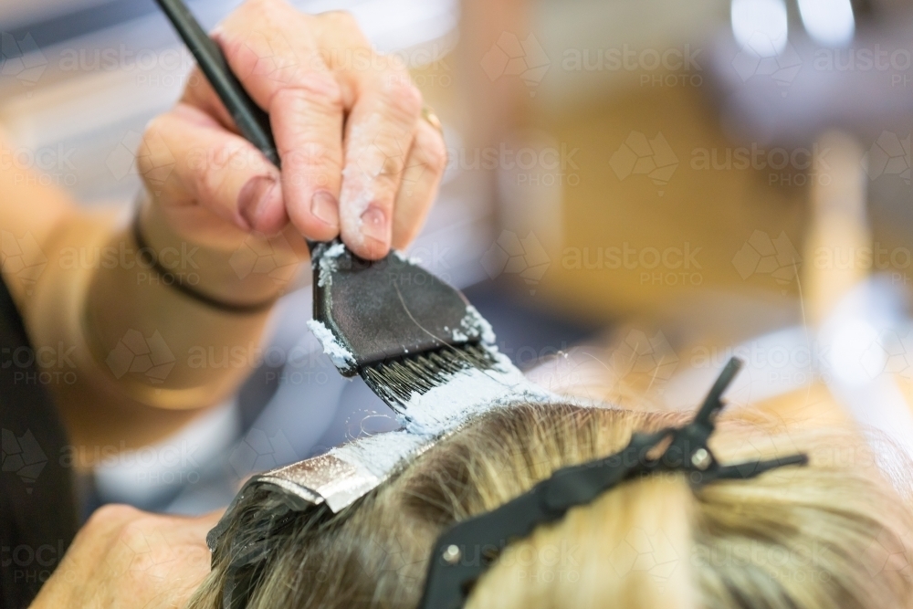 Close up of a hairdresser applying a treatment to a ladies hair - Australian Stock Image