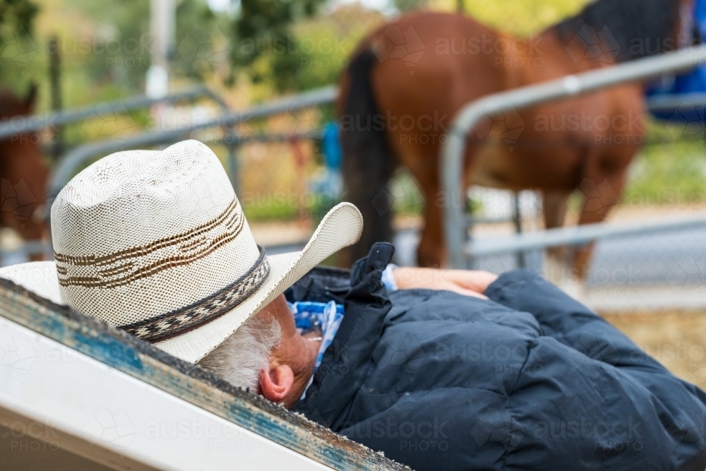 Close up of a horseman sleeping on a ramp with a cowboy hat over his face - Australian Stock Image
