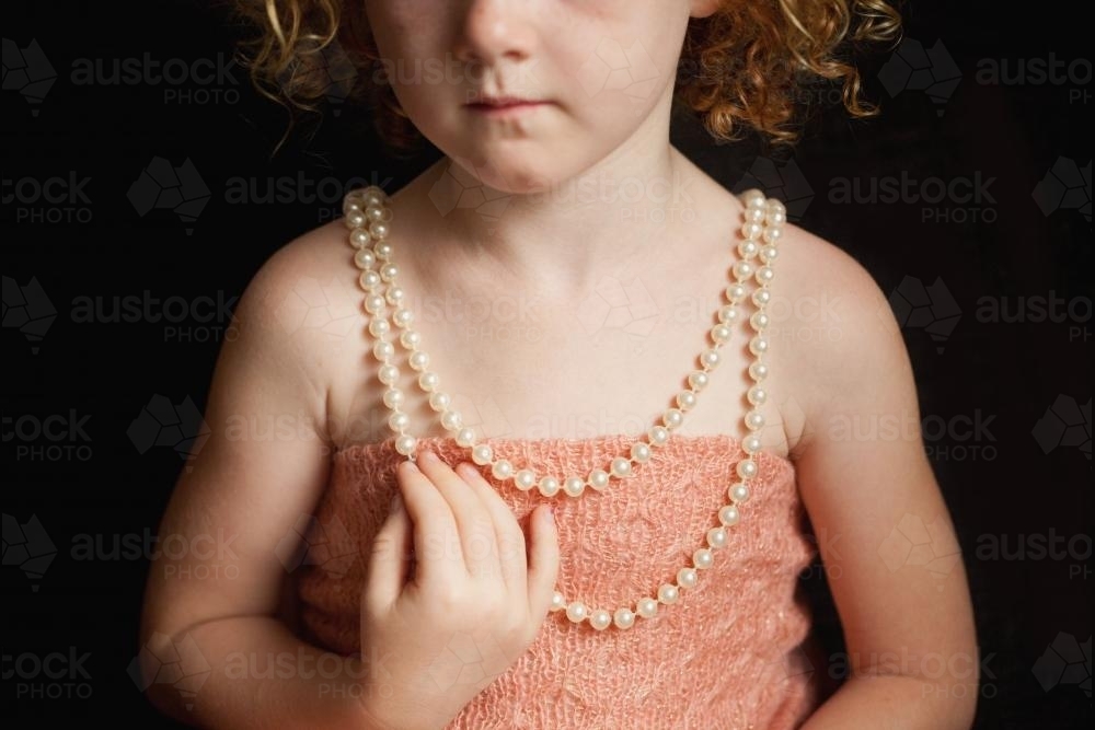 Close up of a little girl wearing a pearl necklace - Australian Stock Image