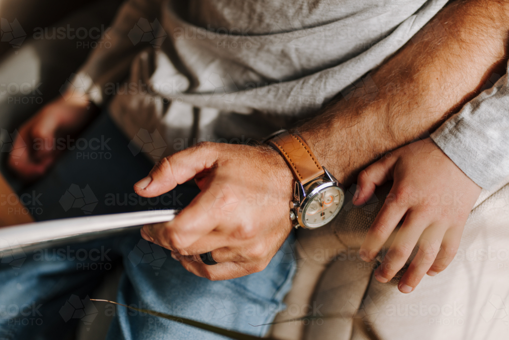 Close up of a man holding a book with son sitting on his lap. - Australian Stock Image