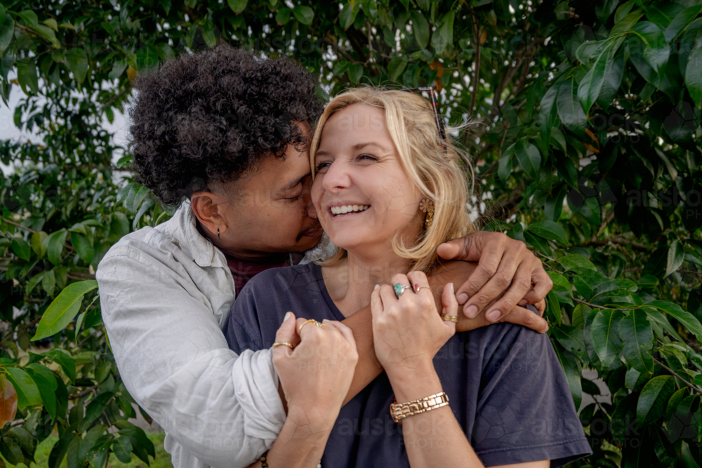 Close up of a man hugging his girlfriend, young happy and in love couple - Australian Stock Image