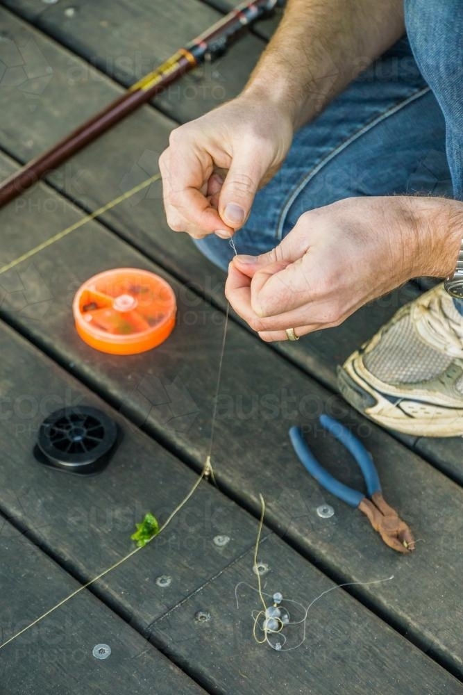 Close up of a man tying a fishing line on jetty - Australian Stock Image