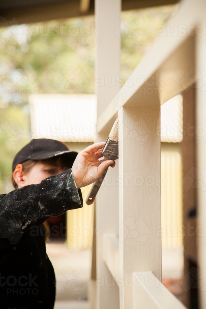 Close up of a painter painting handrails of a home cream colour - Australian Stock Image