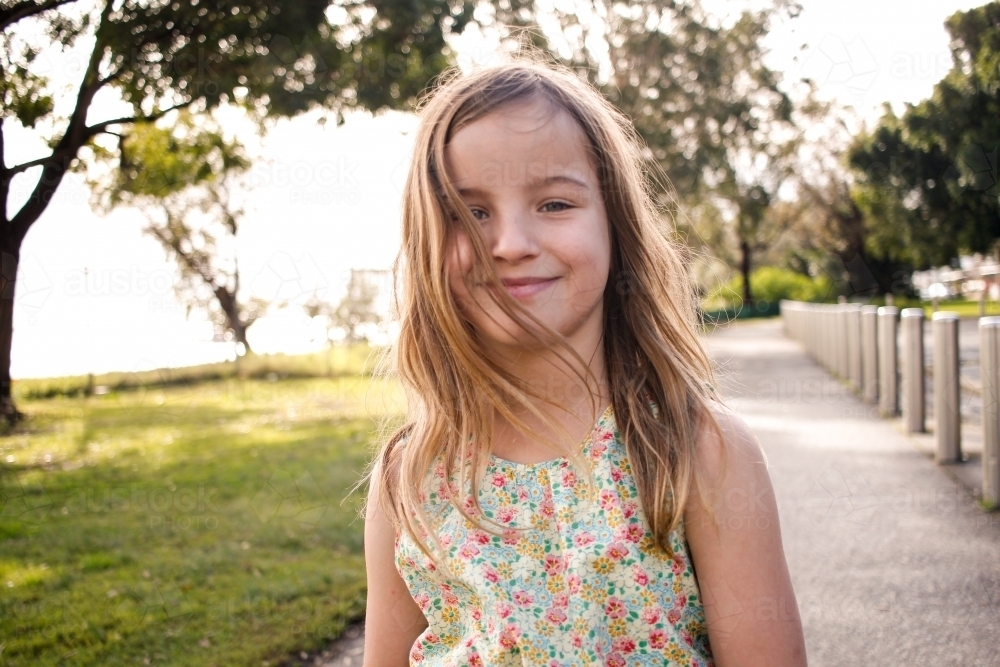 Close-up of a smiling girl walking along a footpath - Australian Stock Image