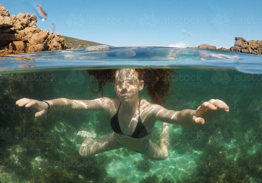 Close up of a teenage girl underwater in an ocean rock pool - Australian Stock Image