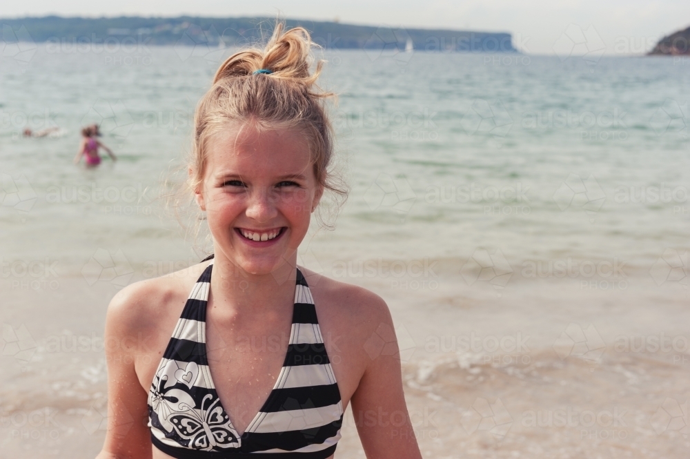 close up of a tween girl smiling to camera, at the beach - Australian Stock Image