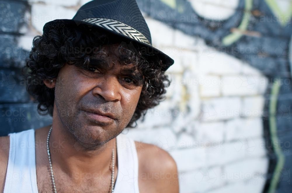 Close Up of a Young Aboriginal Man against a Brick Background - Australian Stock Image