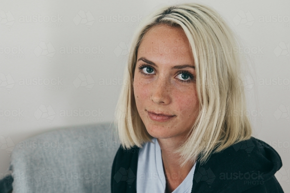 Close up of a young blonde woman looking up towards camera from a chair - Australian Stock Image
