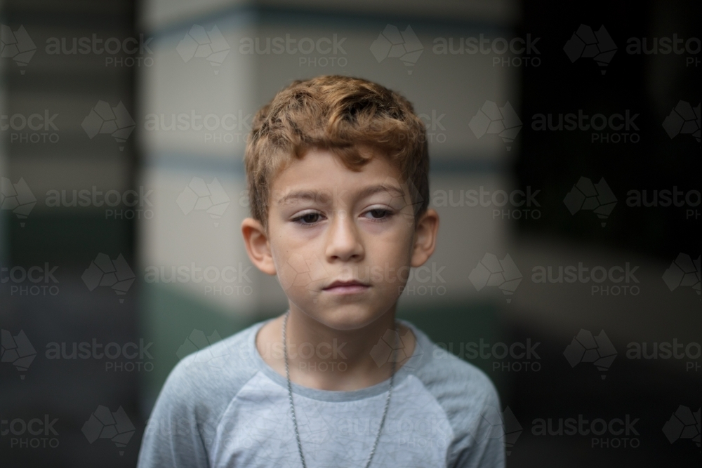 Close-up of a young boy with curly hair looking away - Australian Stock Image