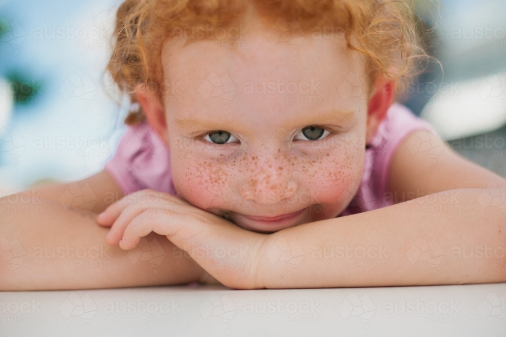 Close up of a young girl resting on her arms - Australian Stock Image
