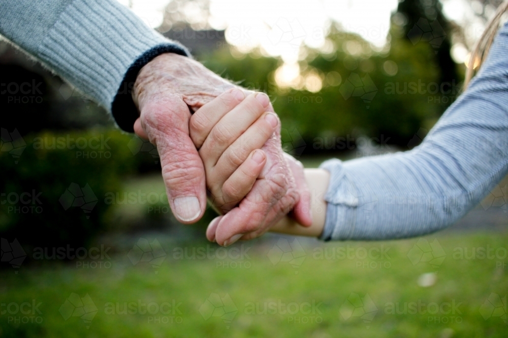 Close-up of aged and young hands holding each other - Australian Stock Image