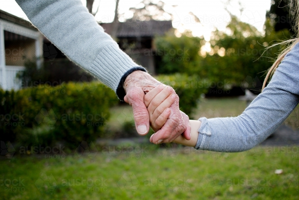 Close-up of aged and young hands holding each other - Australian Stock Image