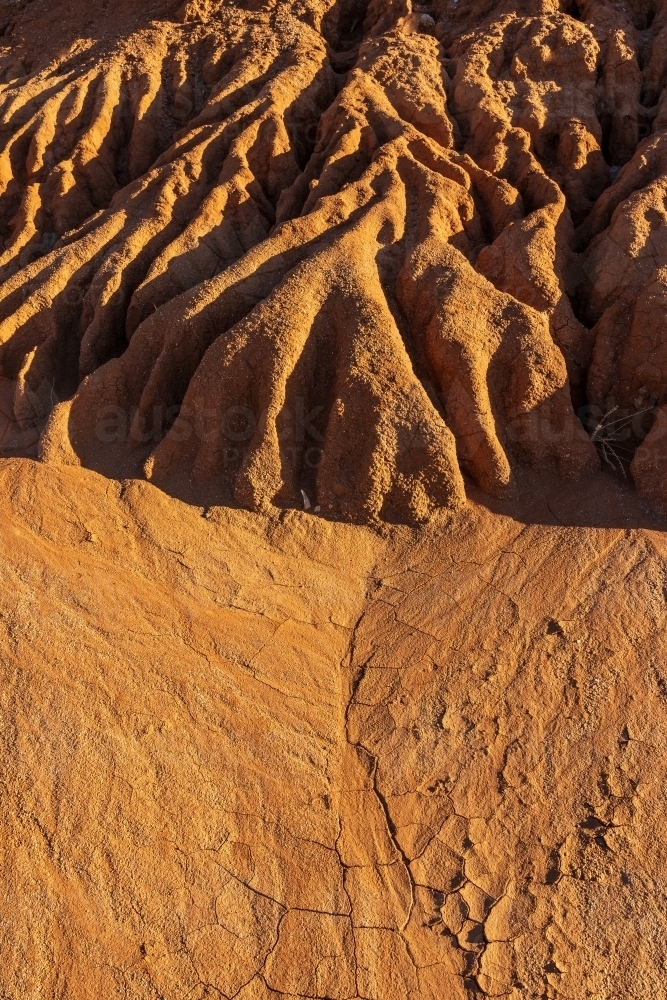 Close up of an eroded river bank of rich red dirt and cracking mud - Australian Stock Image
