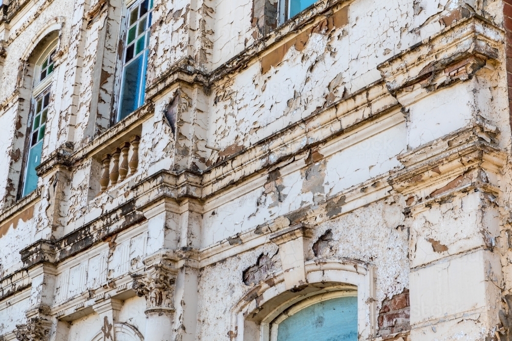 Close up of an old derelict buildings weathered facade with paint and render peeling away - Australian Stock Image