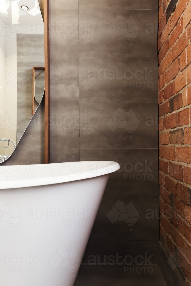 Close up of bath end against grey tiled wall background with text space - Australian Stock Image