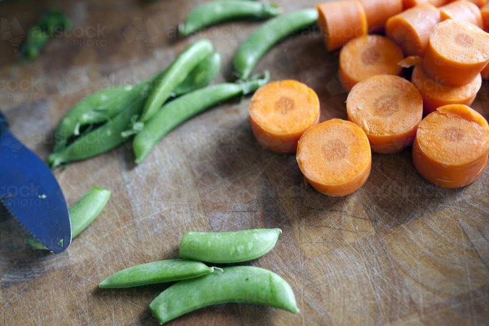 Close up of beans and carrots on chopping board - Australian Stock Image