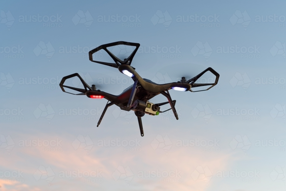 Close-up of black drone, UAV, RPAs flying in a park at sunset - Australian Stock Image