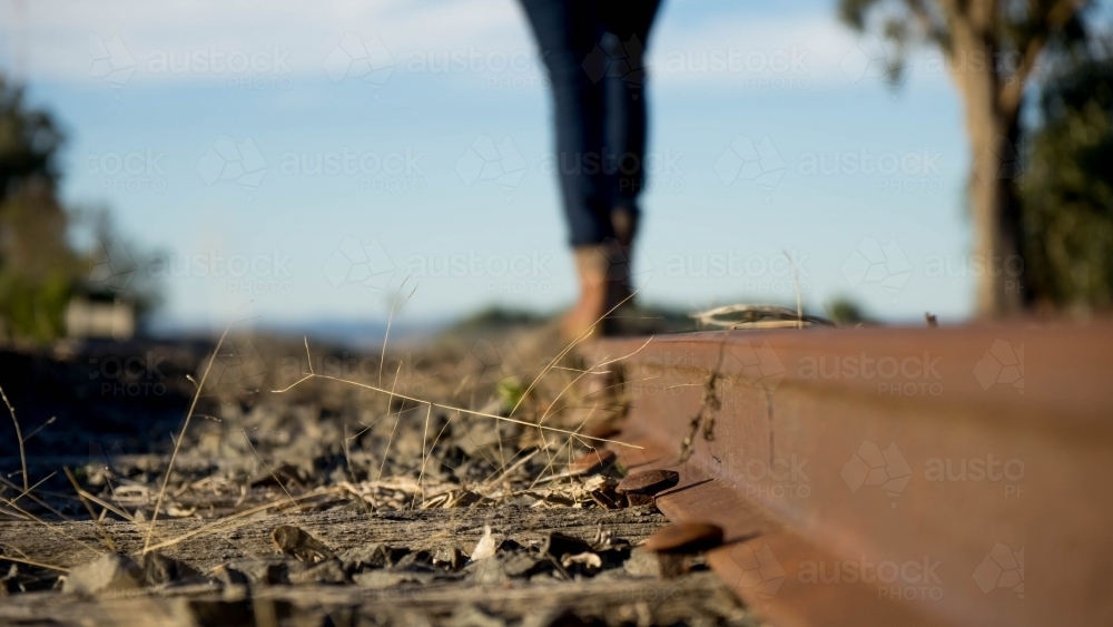 Close up of bolts on railway track with legs in background - Australian Stock Image