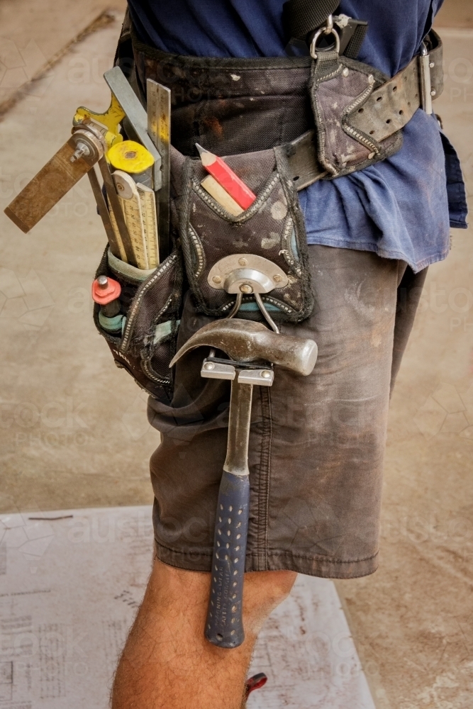 Close-up of builder wearing shorts and tool belt on construction site - Australian Stock Image