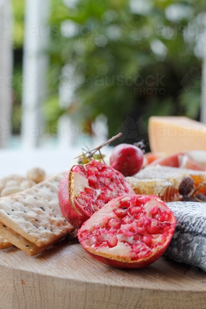 Close up of cheese board with cheese, crackers and pomegranates - Australian Stock Image