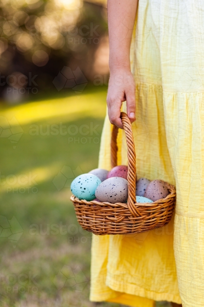 Close up of child holding wooden basket of speckled Easter eggs with copy space - Australian Stock Image