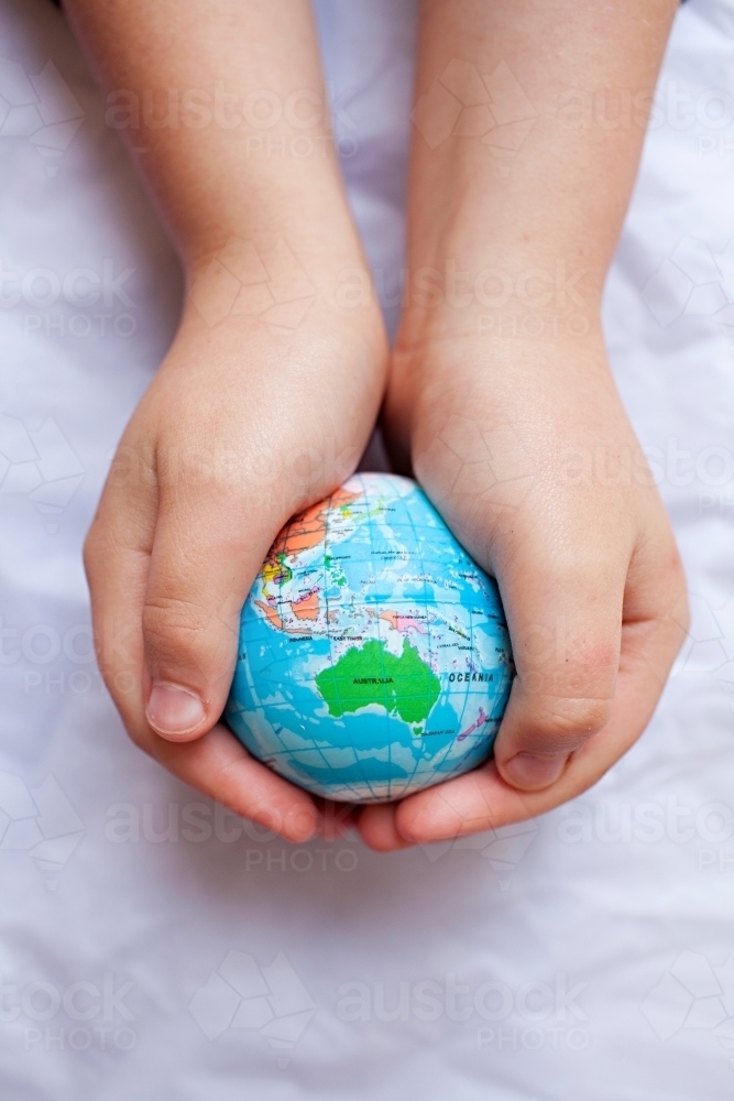 Close up of child's hands holding world globe with Australia map - Australian Stock Image