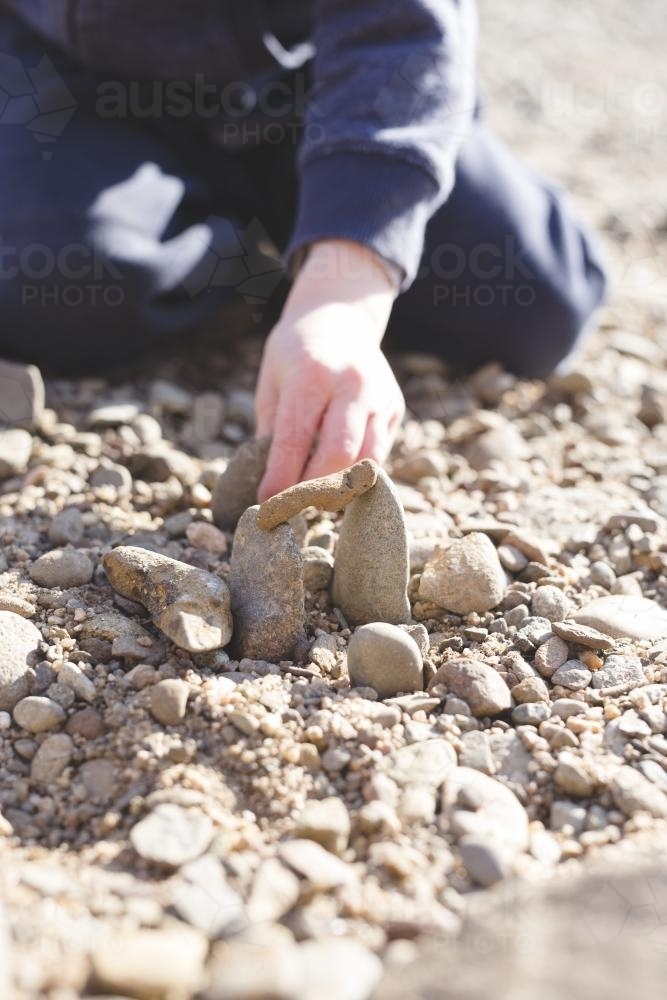 Image of Close up of child stacking rocks - Austockphoto