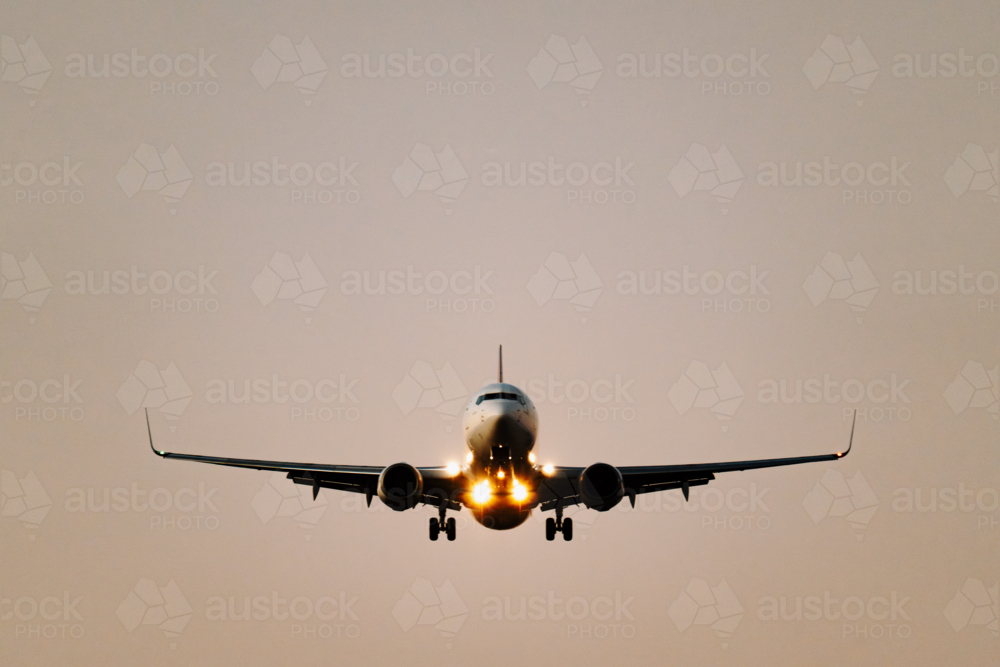 Close up of commercial airplane ready to land on the runway at sunset - Australian Stock Image