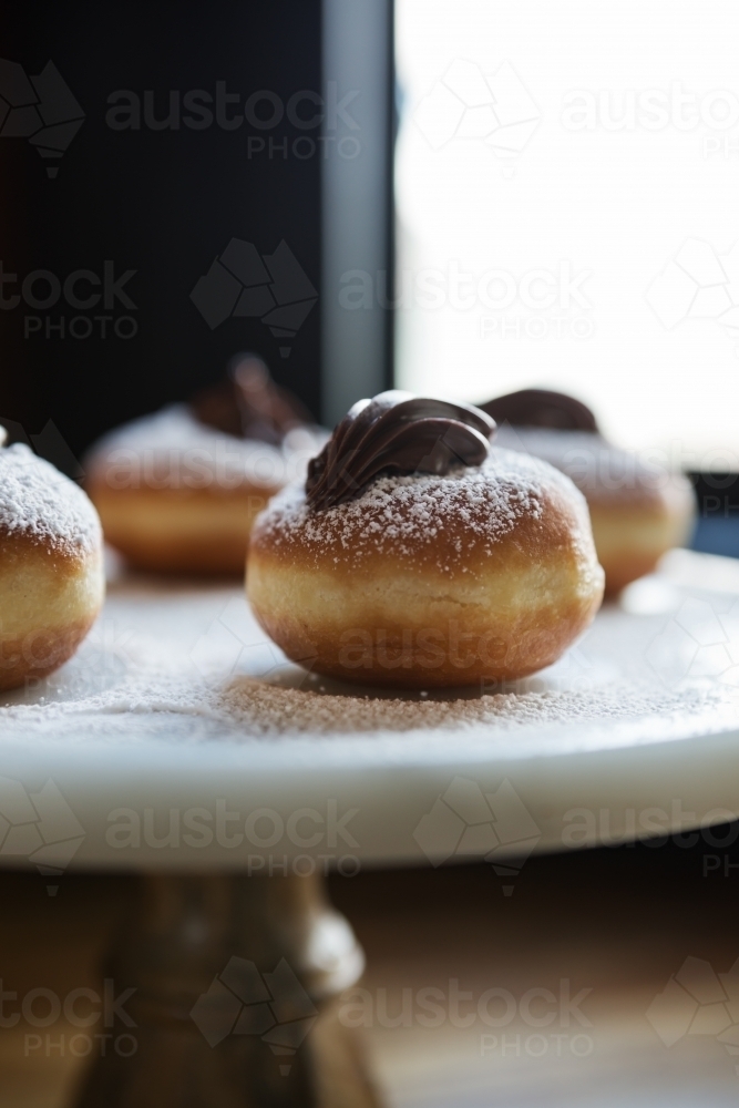 Close up of delicious chocolate topped donut on a vintage cake stand in a restaurant - Australian Stock Image