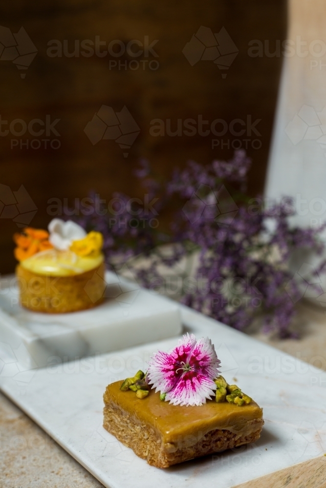 Close up of dessert cakes garnished with edible flowers - Australian Stock Image