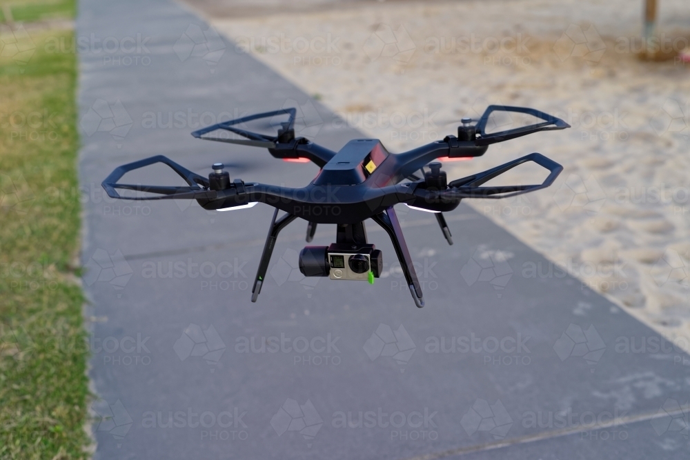 Close up of drone with camera attached flying in an empty park UAV, RPAS - Australian Stock Image