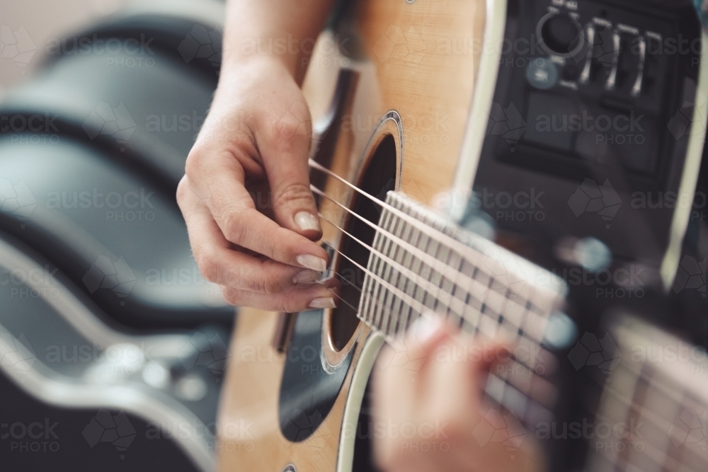 Close up of female hands playing an acoustic guitar - Australian Stock Image