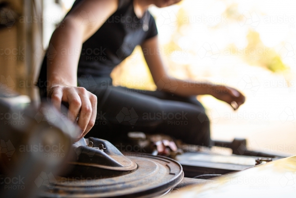 Close-up of female mechanic's hand fixing a car engine - Australian Stock Image