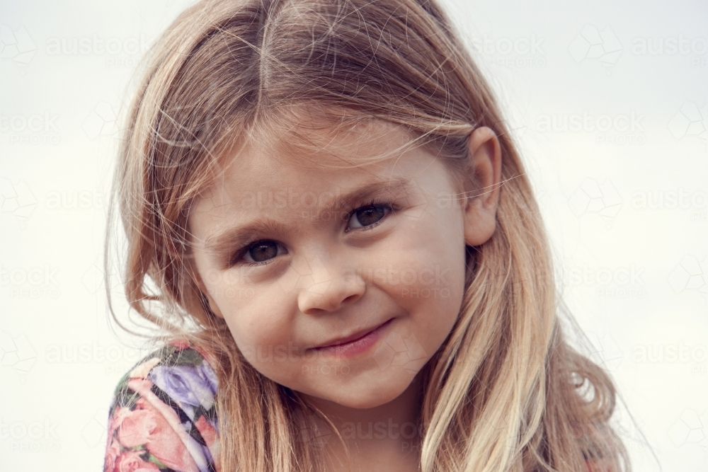 Close up of five year old girl with blonde hair smiling - Australian Stock Image