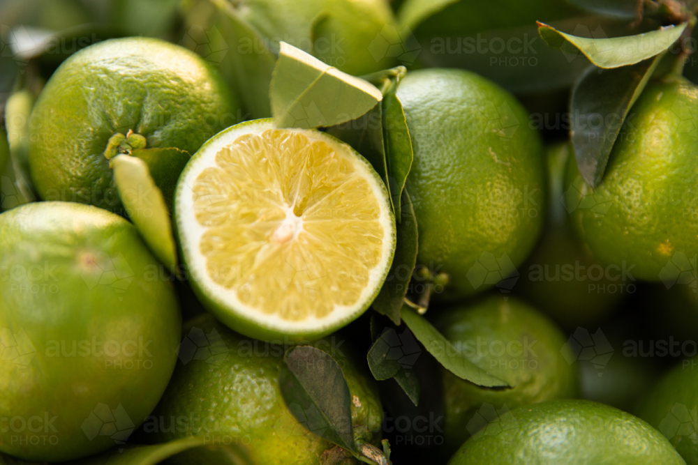 Close‑up of fresh green limes piled together with one lime cut in half - Australian Stock Image
