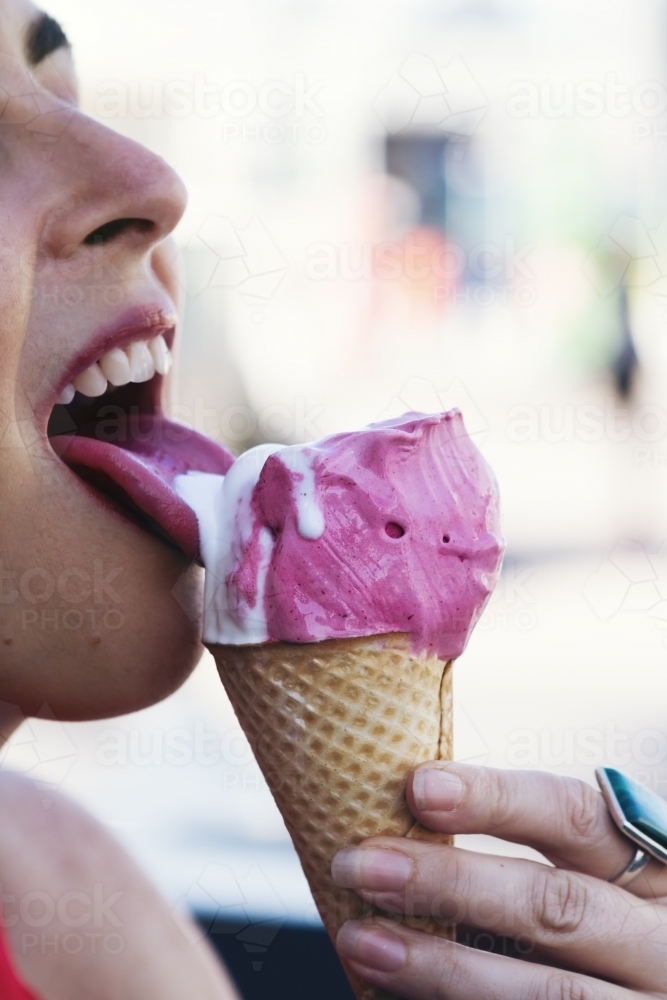 Close up of girl licking an ice cream cone - Australian Stock Image