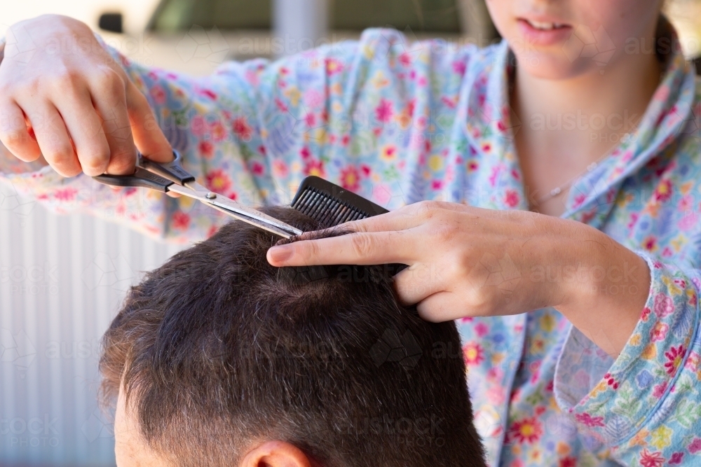 Close up of girl's hands cutting a man's hair - Australian Stock Image