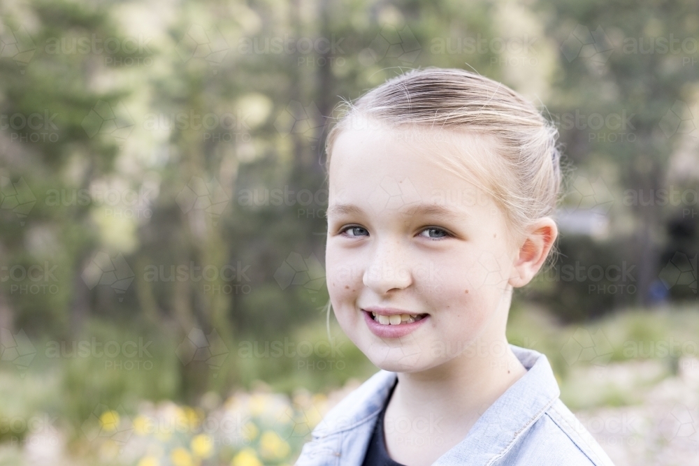 Close up of girl smiling at the camera outdoors - Australian Stock Image
