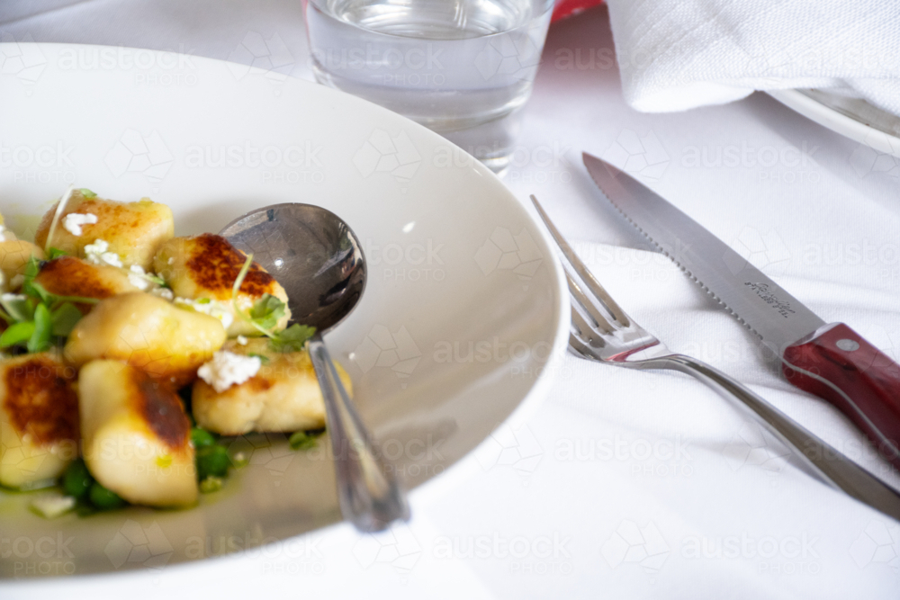 Close up of gnocchi meal on a table with cutlery - Australian Stock Image