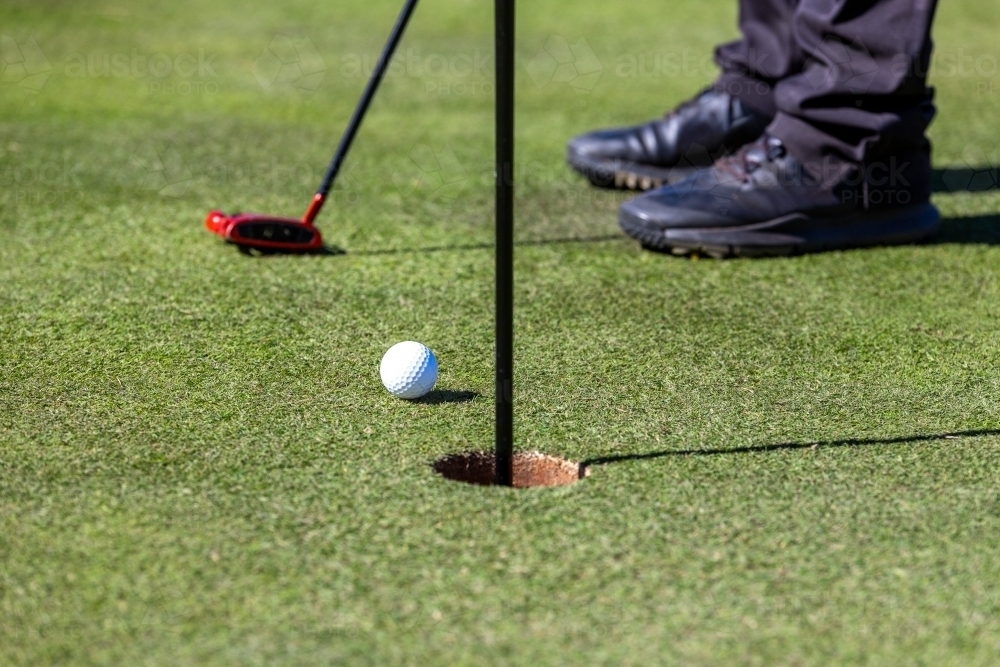 Close-up of golf ball on course near hole - Australian Stock Image