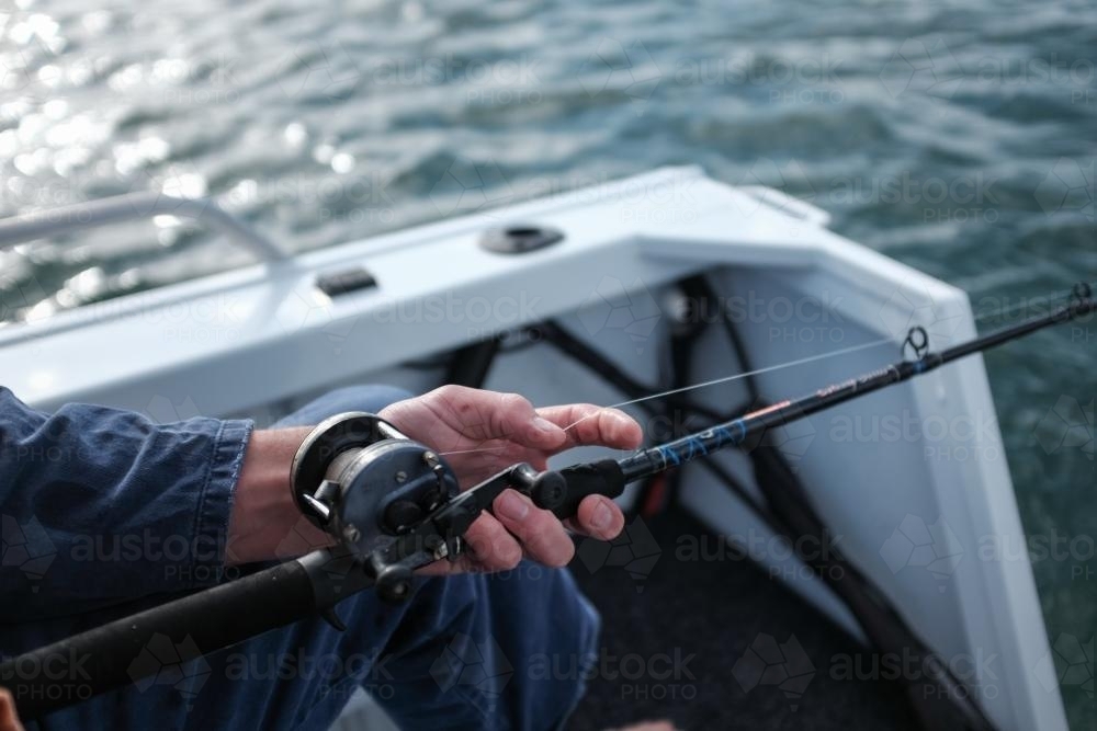 close up of hand and fishing reel while fishing - Australian Stock Image