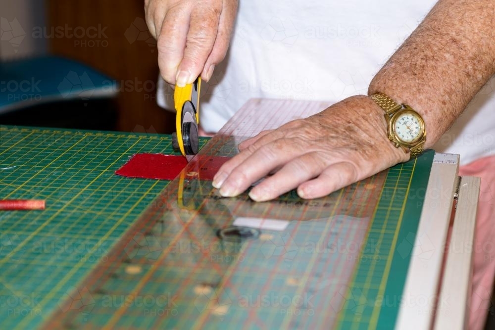 Close up of hands, cutter and ruler for blocking and quilting - Australian Stock Image