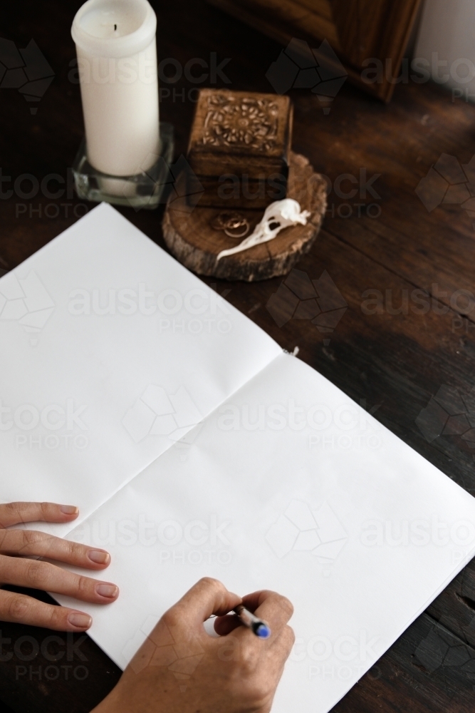 Close up of hands holding a pen write in a blank notebook - Australian Stock Image