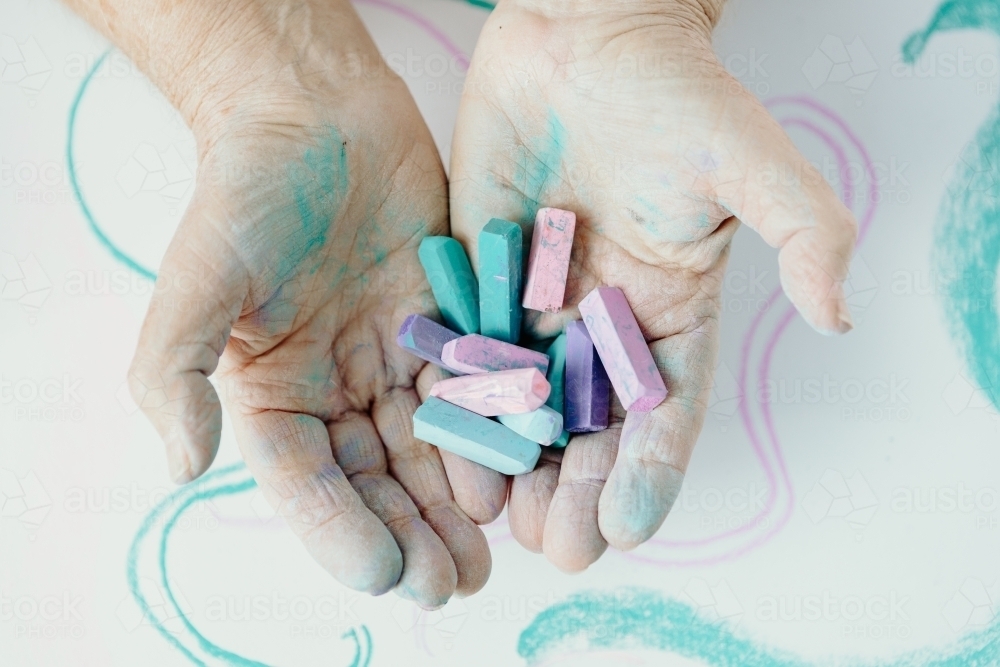 Close up of hands holding pastel paints - Australian Stock Image