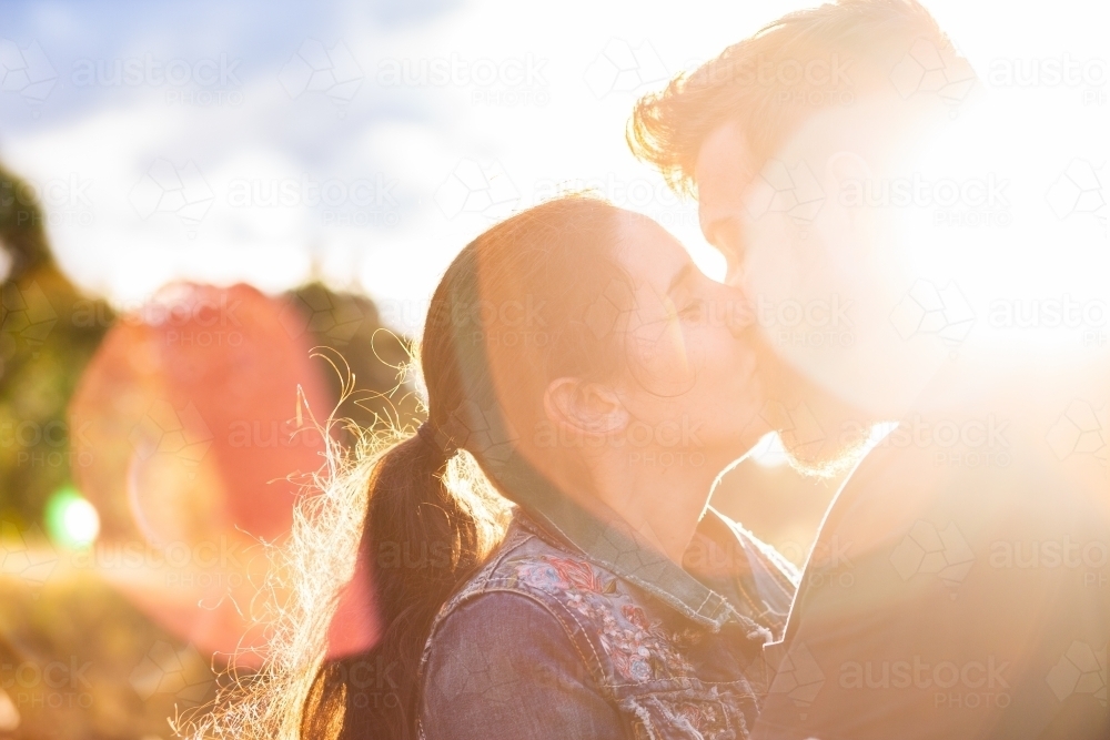 Close up of happy couple kissing with light flare - Australian Stock Image
