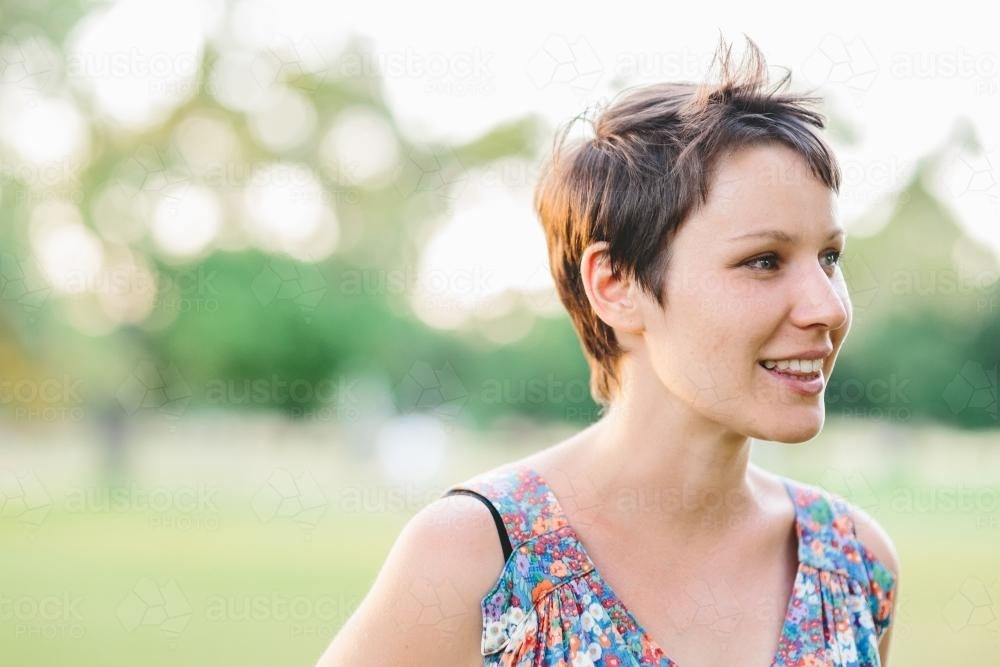 Close up of happy smiling woman in summer dress at dusk - Australian Stock Image