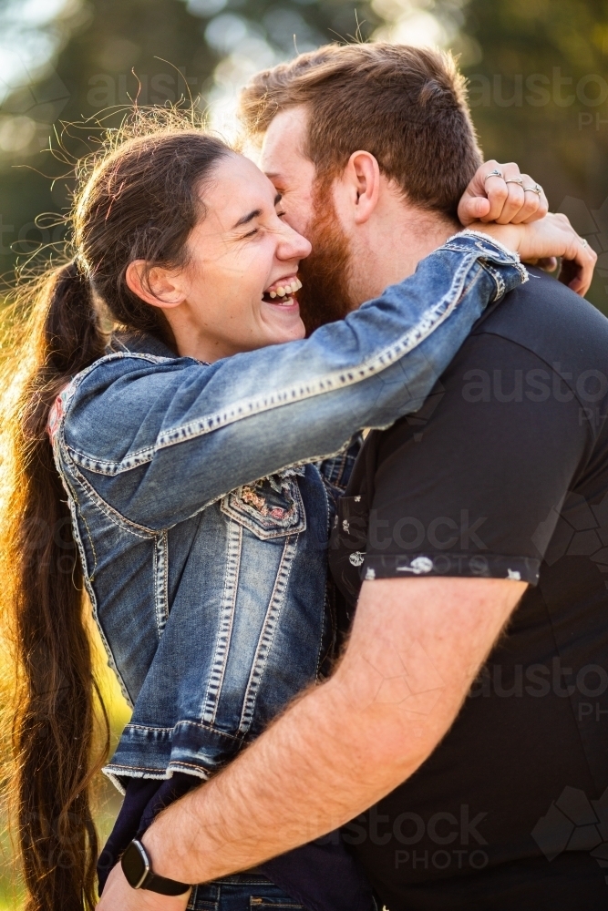 Close up of happy young couple hugging and laughing together - Australian Stock Image