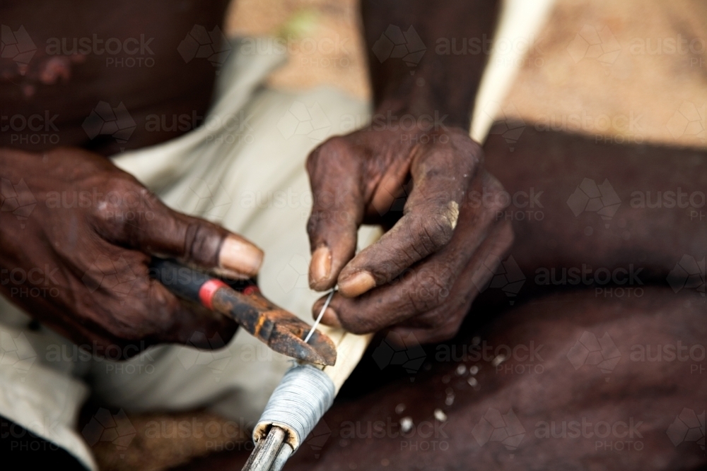 Close up of indigenous persons hands working with tools - Australian Stock Image