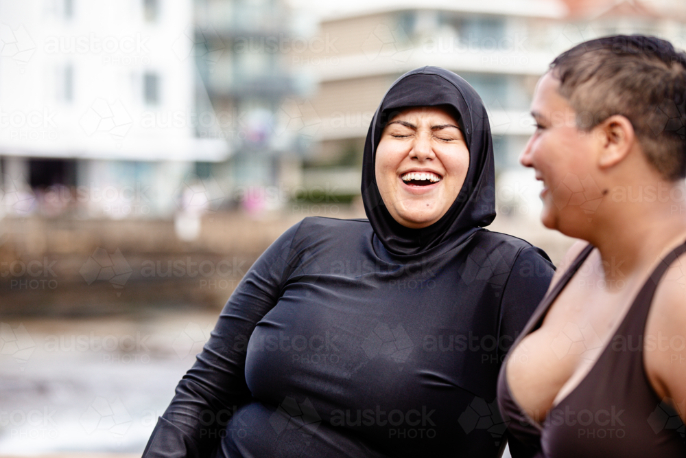 Close up of Italian-Filipino woman having a conversation with French Islander woman in tidal pool - Australian Stock Image