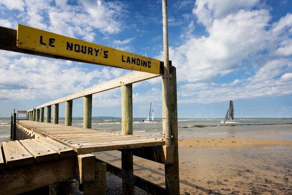 Close up of jetty with catamarans sailing in background - Australian Stock Image